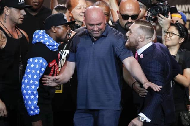UFC president Dana White, center, intervenes as boxer Floyd Mayweather Jr., left, and mixed martial arts fighter Conor McGregor exchange words
