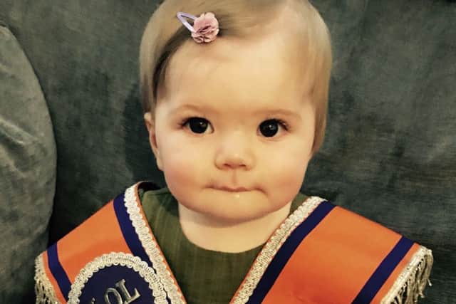 Pixie-Molly McKessick, aged 10 months tries on her father's sash before heading to her first Twelfth in Cloughmills