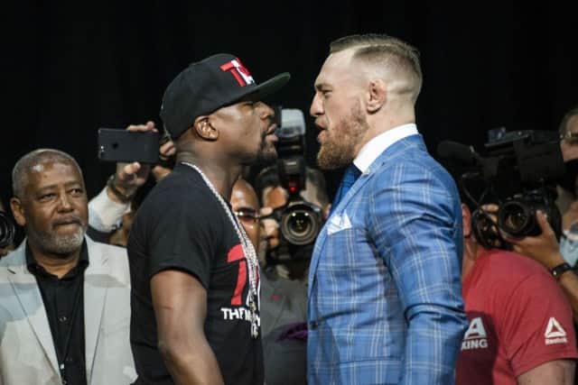Floyd Mayweather, left, and Conor McGregor exchange harsh words during a promotional stop in Toronto