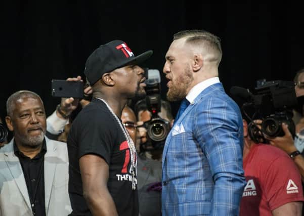 Floyd Mayweather, left, and Conor McGregor exchange harsh words during a promotional stop in Toronto