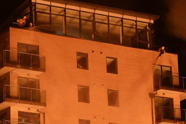 Two firefighters, one in the top left corner of the damaged apartment block and one in the top right, hosed it throughout the bonfire, as did fire crews on the ground, but still it was scorched and windows broke.
Picture by Arthur Allison