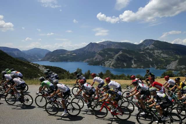 The pack rides next to Serre Poncon lake during the eighteenth stage of the Tour de France cycling race over 179.5 kilometers (111.5 miles) on Thursday, July 20, 2017. It is one of those sporting events in which the oldest ever winner is aged 36. (AP Photo/Peter Dejong)