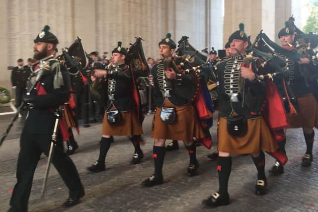 The pipes and drums of the Royal Irish Regiment leading the standard bearers and veterans on a march through the Menin Gate.