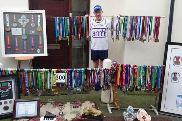 Eugene Oggie Winters with his staggering collection of medals  from running all around the world
