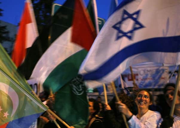 Israeli left-wing activists in Jerusalem hold an Israeli flag and the flags of Arab League countries, In Northern Ireland, the Palestinian and Israeli flag fly in different areas. (AP Photo/Kevin Frayer)