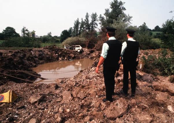 Officers look down at the vast crater caused by the explosion which killed three colleagues and  a nun