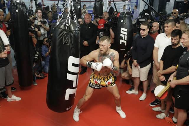 Conor McGregor hits a heavy bag while surrounded by media and supporters