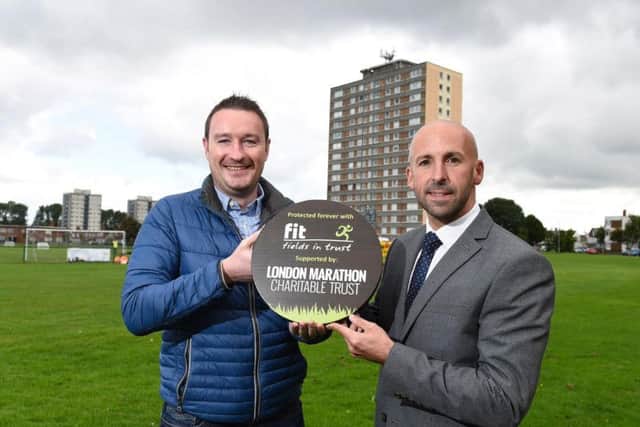 Cllr Adam Newton of Belfast City Council's People and Communities Committee receiving a plaque from Terry Housden (Development Manager for Fields in Trust South East England & Northern Ireland) on East Belfast's Cregagh Green, the football pitch where George Best first kicked a ball.