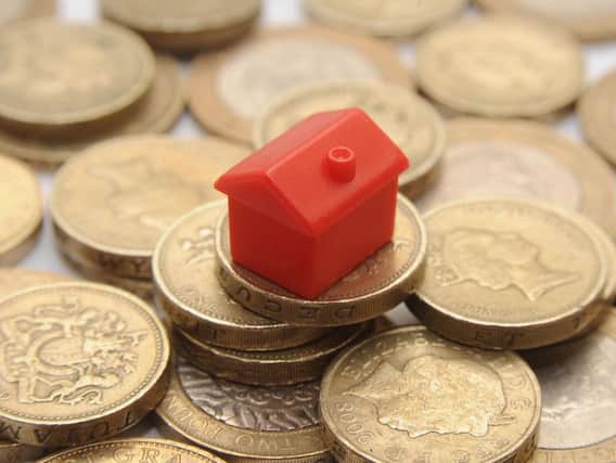 File photo dated 27/01/15 of a plastic model of a house on a pile of one pound coins, as house prices are around 10,000 higher on average than a year ago but the annual pace of growth is slowing, official figures show
