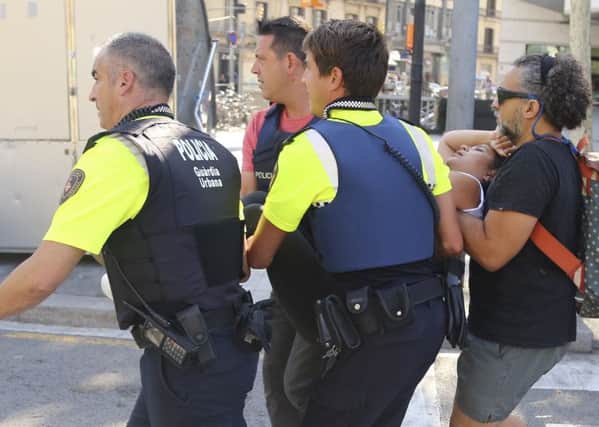 A person is carried in Barcelona, Spain, Thursday, Aug. 17, 2017 after a white van jumped the sidewalk in the historic Las Ramblas district, crashing into a summer crowd of residents and tourists and injuring several people, police said. (AP Photo/Oriol Duran)