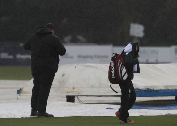 People on the pitch during a heavy shower as they await a pitch inspection during the One Day International Series at the Civil Service Cricket Club