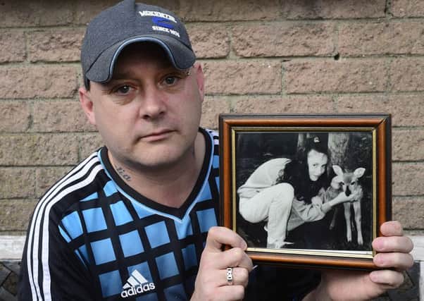 Gary Murray holding a photo of his 13-year-old sister Leanne
