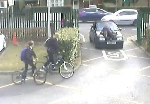 A screen grab from the footage showing the incident where a parent drove at a teacher at the school gates of The Winston Churchill School in Woking, carrying him on the bonnet of the car before he was thrown to the ground