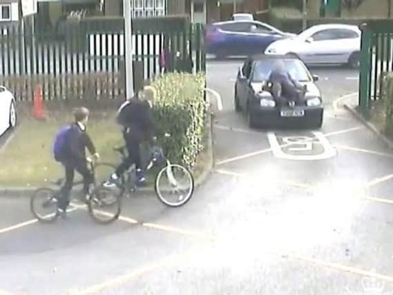 A screen grab from the footage showing the incident where a parent drove at a teacher at the school gates of The Winston Churchill School in Woking, carrying him on the bonnet of the car before he was thrown to the ground