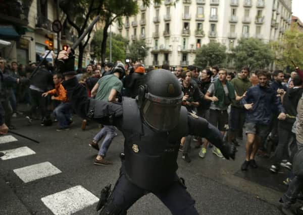 Spanish riot police swings a club against would-be voters near a school assigned to be a polling station by the Catalan government in Barcelona, Spain, Sunday, Oct. 1, 2017. Spanish riot police have forcefully removed a few hundred would-be voters from several polling stations in Barcelona. (AP Photo/Manu Fernandez)