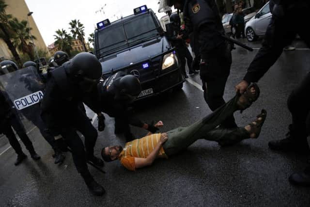 Spanish National Police officers drags a man trying to block a police van outside the Ramon Llull school assigned to be a polling station by the Catalan government in Barcelona, Spain, early Sunday, 1 Oct. 2017. Catalan pro-referendum supporters vowed to ignore a police ultimatum to leave the schools they are occupying to use in a vote seeking independence from Spain. (AP Photo/Emilio Morenatti)