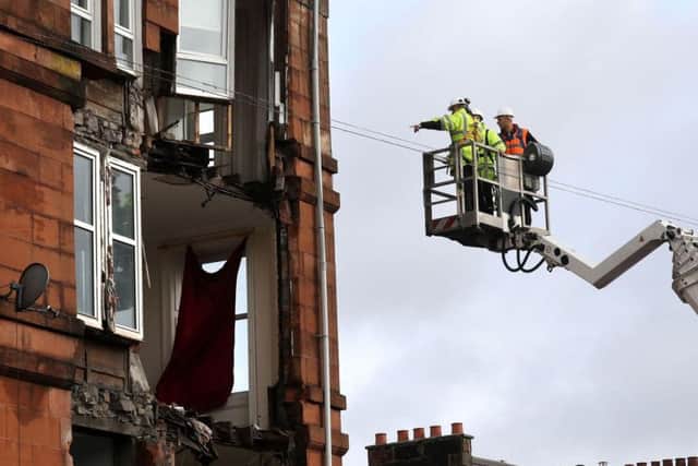 Workmen survey the damage to a block of flats in Crosshill, in the south side of Glasgow, after part of the front was brought down in high winds as Storm Ophelia sweeps across Scotland