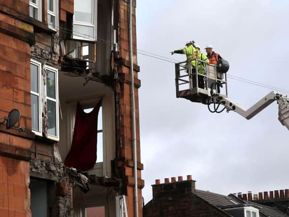 Workmen survey the damage to a block of flats in Crosshill, in the south side of Glasgow, after part of the front was brought down in high winds as Storm Ophelia sweeps across Scotland