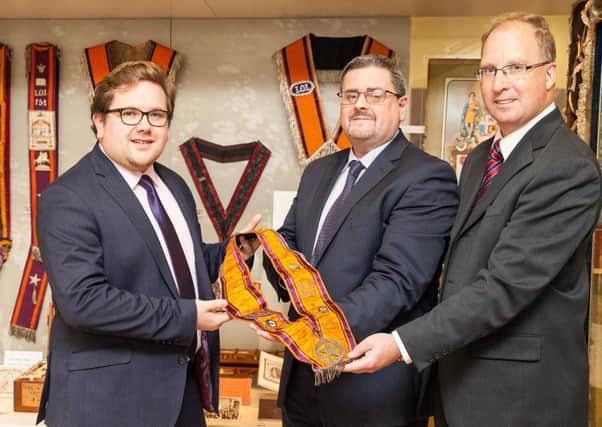 Jonathan Mattison, Museum of Orange Heritage curator (centre), receives the Orange collarette once belonging to J M Andrews (inset) from Limavady trustees Aaron Callan and Keith Thompson