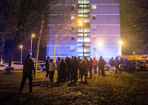 People gather at the scene of a fire at Coolmoyne House in Dunmurry, near Belfast, where residents have been evacuated from the building