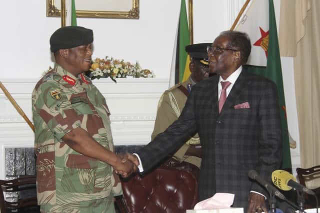 Zimbabwean President Robert Mugabe, right, shakes hands with Army General Constantino Chiwenga